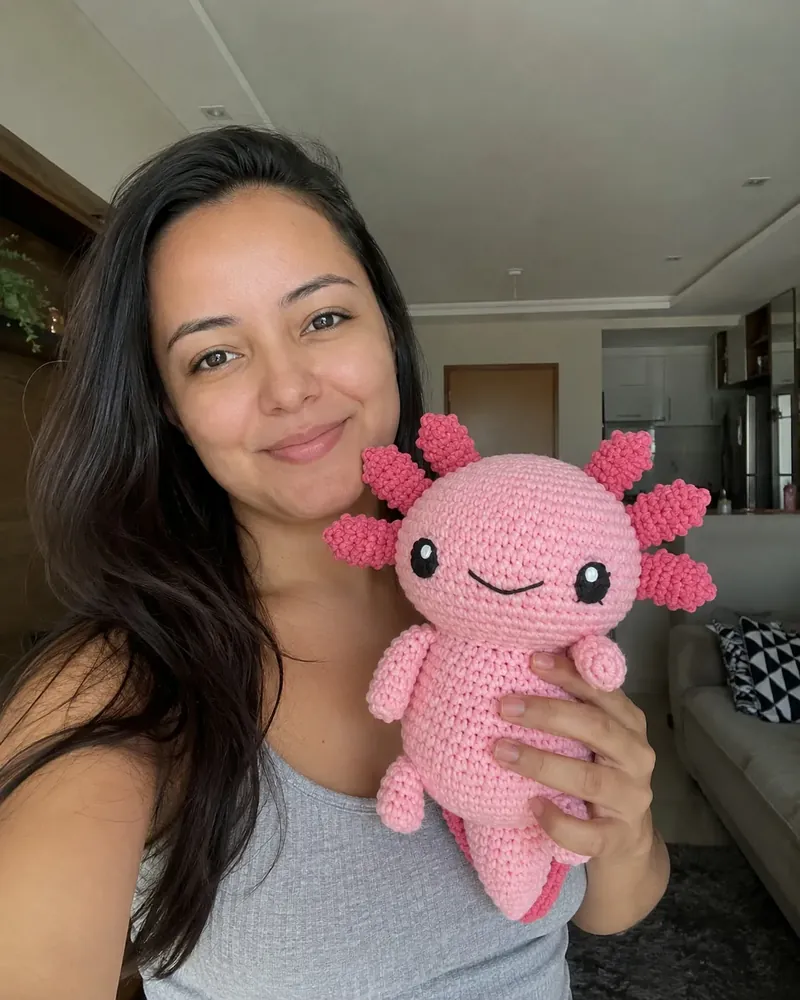 Clienta sosteniendo un ajolote rosa de crochet hecho por ella.